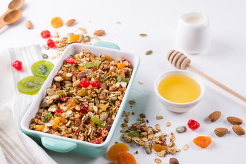 Baked granola in the baking tray and various delicious ingredients for healthy breakfast