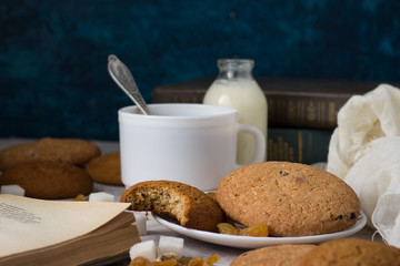 Oatmeal cookies, Books, Oatmeal Flakes, Cup of Coffee with Milk, Raisins on a light background. The concept of Good Morning and Breakfast