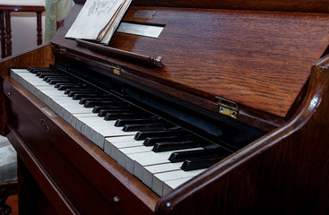 Close-up of an old piano and a music notebook. Diagonal view of piano keys. Piano is ready to play
