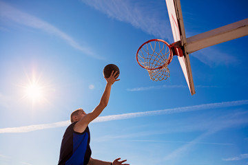 Slam Dunk. Side view of young basketball player making slam dunk