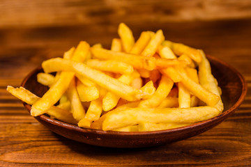 Ceramic plate with french fries on wooden table