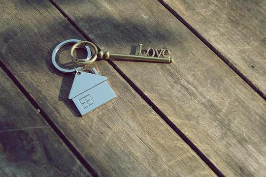 Home key with love house keyring on wood background