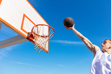 Slam Dunk. Side view of young basketball player making slam dunk © FS-Stock