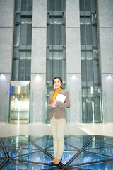 Smiling optimistic confident young mixed race businesswoman holding tablet and looking at camera in urban contemporary office