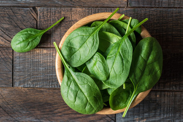 Baby spinach in wooden bowl, top view selective focus. Dieting, healthy eating, healthy lifestyle, fitness, weight loss concept