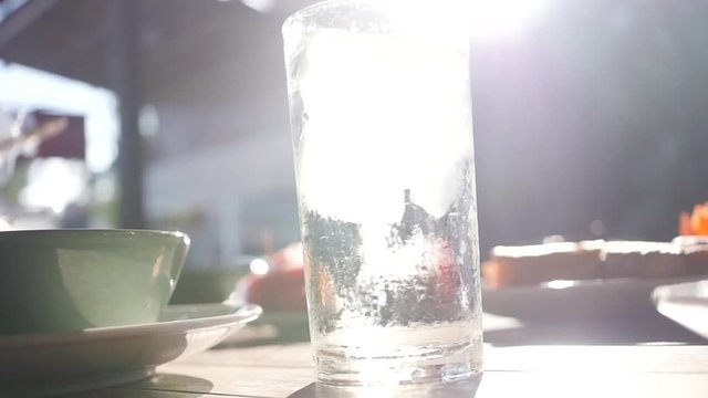 Put the ice in a glass of water in the sun at the dinner table. slow motion. 1920x1080. full hd
