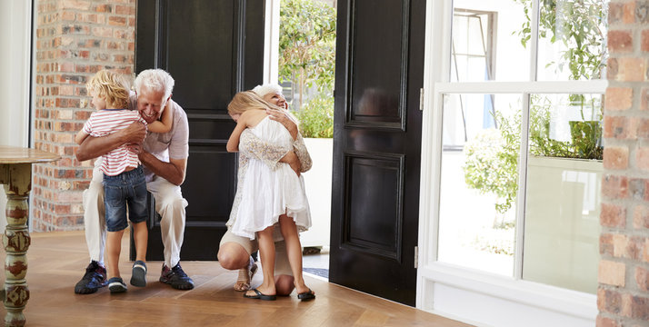 Visiting grandparents bend and kneel to hug grandchildren