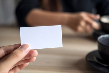 A businessman holding an empty business card with businesswoman in background