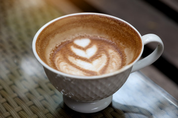 Closeup image of a cup of hot latte coffee with heart latte art on table