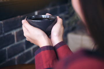 Closeup image of a woman holding a coffee cup before drinking in cafe