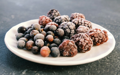 Frozen berries on a white saucer BlackBerry and black currant.