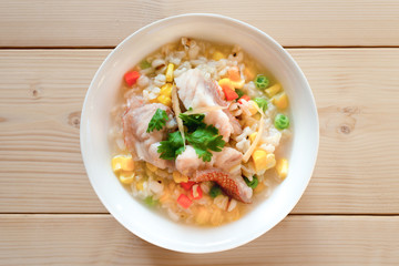 Fish and cereal porridge,top view.Fish in soft boiled cereal and rice  for breakfast on wooden table ,healthy food concept ..