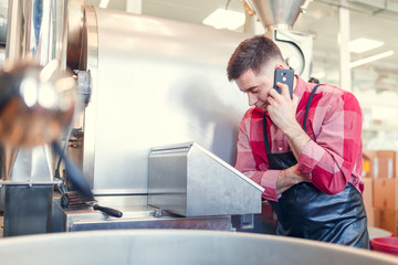 Image of businessman talking on phone at computer of industrial machine