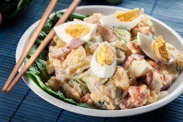 Delicious potato salad with ham, egg and cucumber