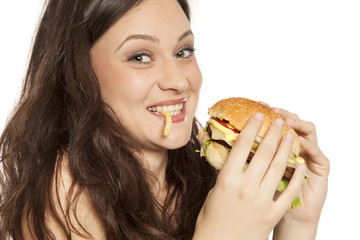 young beautiful greedy woman eating a hamburger on white background