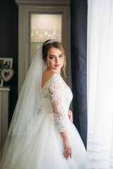 Fototapeta premium Portrait of a bride in a wedding dress. The bride dresses in the hotel.