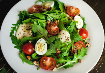 Fresh salad with tomatoes, mixed greens ,nuts, eggs, on wooden background . Healthy food.