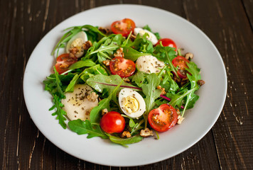 Fresh salad with tomatoes, mixed greens ,nuts, eggs, on wooden background . Healthy food.