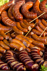 assorted sausages grilled on skewers on a large plate, mushrooms on the grill. Street festival food.