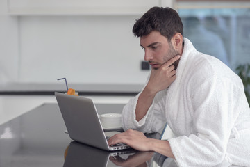 A man in a robe with a laptop at home