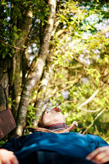 a blurred man lies on a bench and relaxes in the summer in the sun, the hat on his face is isolated, the butterfly on the hat is isolated