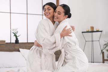Obraz premium LGBT community. Positive lesbian couple hugging each other while being in a spa salon