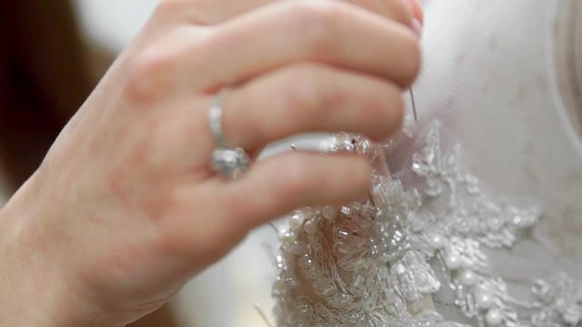 Close-up fashion designer for brides in his Studio pins needles lace wedding dress. Seamstress creates an exclusive wedding dress. Secure with pins and needles outline. Small private business