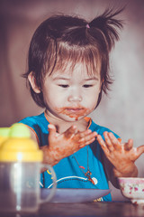 Child eating with a stained face. Do it yourself concept. Vintage tone.