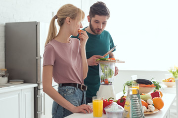 boyfriend preparing vegetable juice with juicer at kitchen, vegan concept