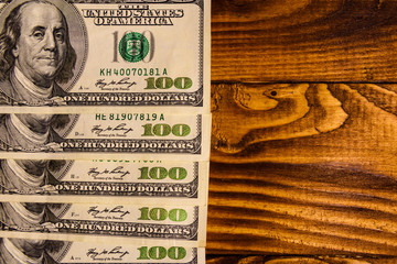 Many one hundred dollar bills on wooden table