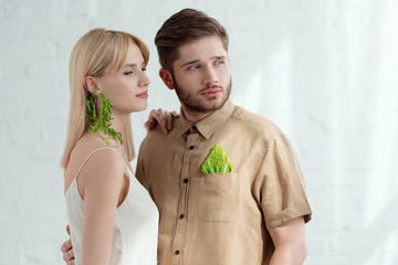 woman with earring made of arugula and boyfriend with savoy cabbage leaf in pocket, vegan lifestyle...