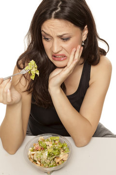 disgusted woman eating a caaesar salad to go on white background