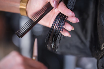 Cropped shot of a female hairdresser cutting clients hair with scissors at beauty salon
