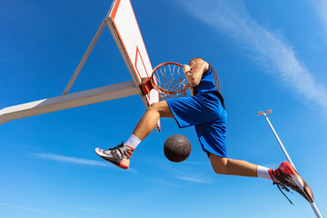 Slam Dunk. Side view of young basketball player making slam dunk © FS-Stock