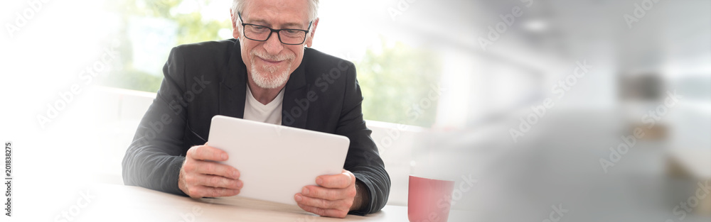 Wall mural portrait of senior businessman working on tablet