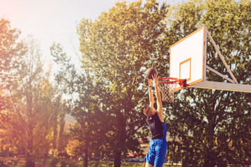 Street basketball player performing power slum dunk