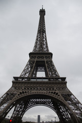 Fototapeta na wymiar the eiffel tower from the ground up on a cloudy day with clouds and even lighted sky