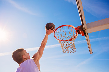 Slam Dunk. Side view of young basketball player making slam dunk