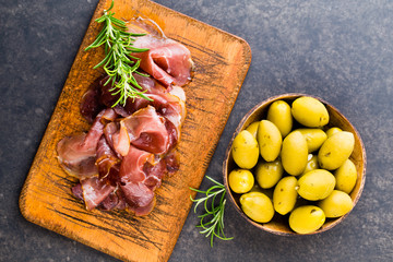 Prosciutto with rosemary on a black background.