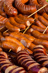 assorted sausages grilled on skewers on a large plate, mushrooms on the grill. Street festival food.