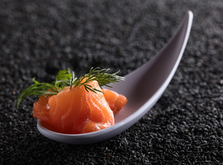 Salted salmon with dill on the background of black sesame.
