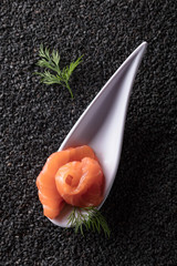 Salted salmon with dill on the background of black sesame.