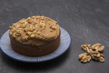 Large coffee and walnut cake on a blue plate with walnuts 