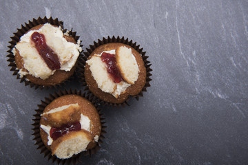 Three raspberry and cream cupcakes on a dark marble background with copy space 