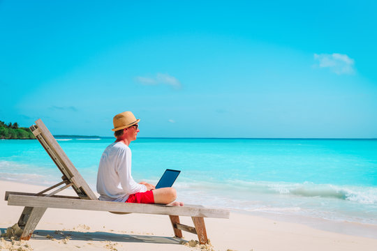 young man working on laptop at beach