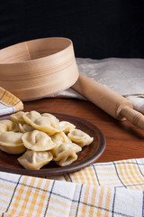 Boiled Ukrainian meat dumplings or ravioli on wooden background.