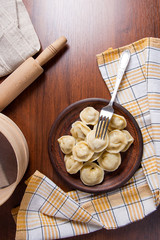 Served in clay plate Ukrainian meat dumplings or ravioli on wooden background..