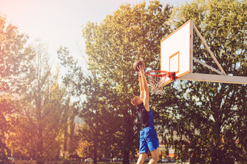 Street basketball player performing power slum dunk