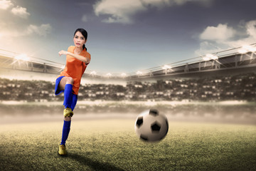Obraz premium Attractive asian footballer woman kicking ball during match