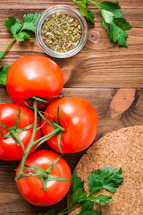 Fresh tomatoes, greens and spices on a wooden background. Space for the inscription. Top View